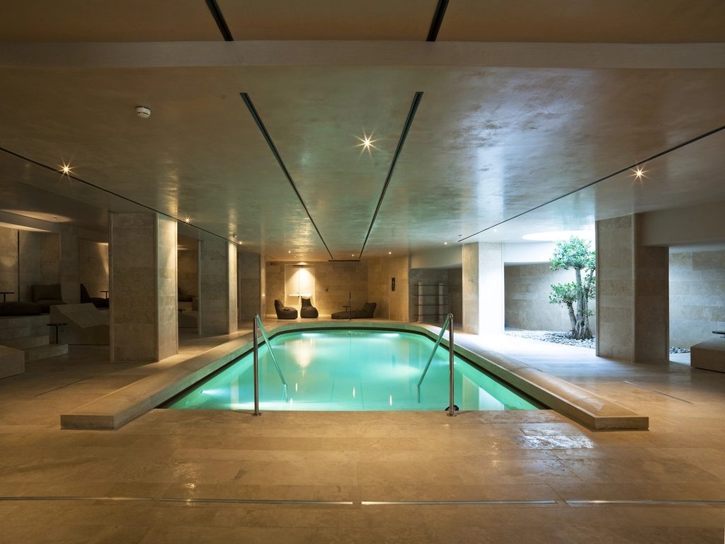 The Wexley indoor pool, softly lit, with stone columns