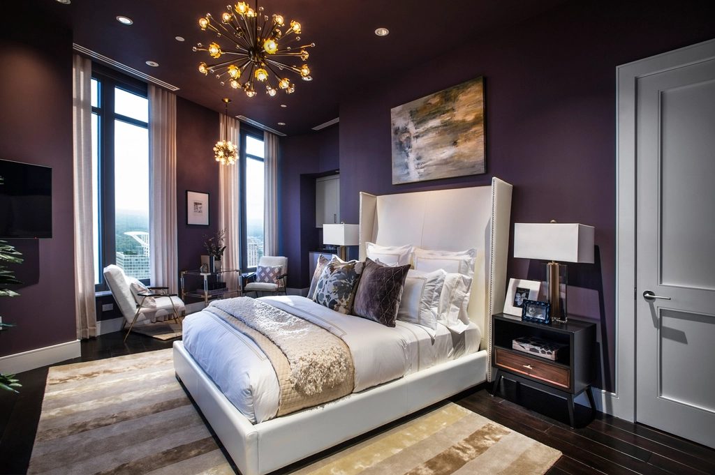 Comfort King room with plum walls, a chandelier and a window onto the city
