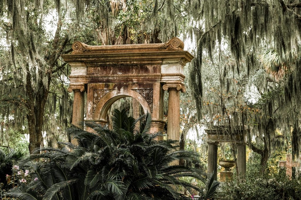 Historic stone gateway under moss-covered oaks